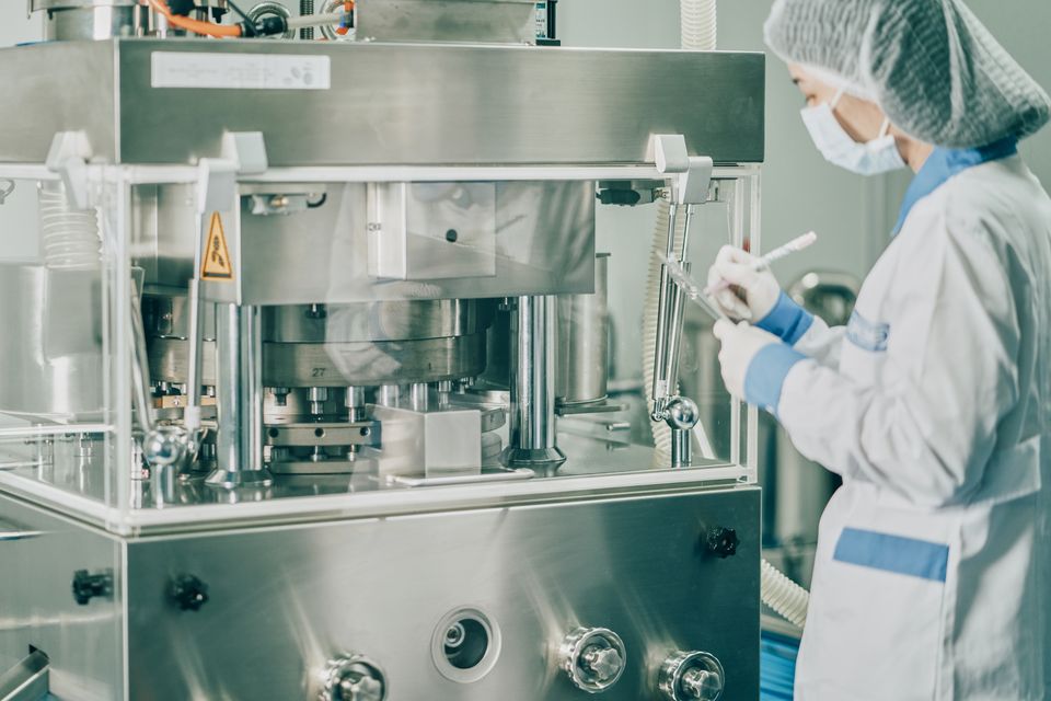 a person in a white robe and mask working in a machine